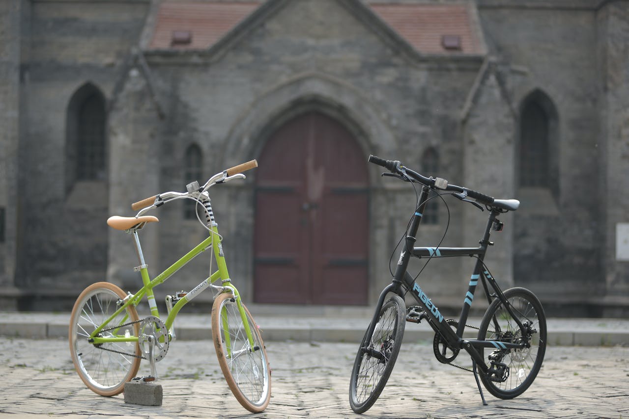 Two modern bicycles parked on cobblestone street in front of historic building.